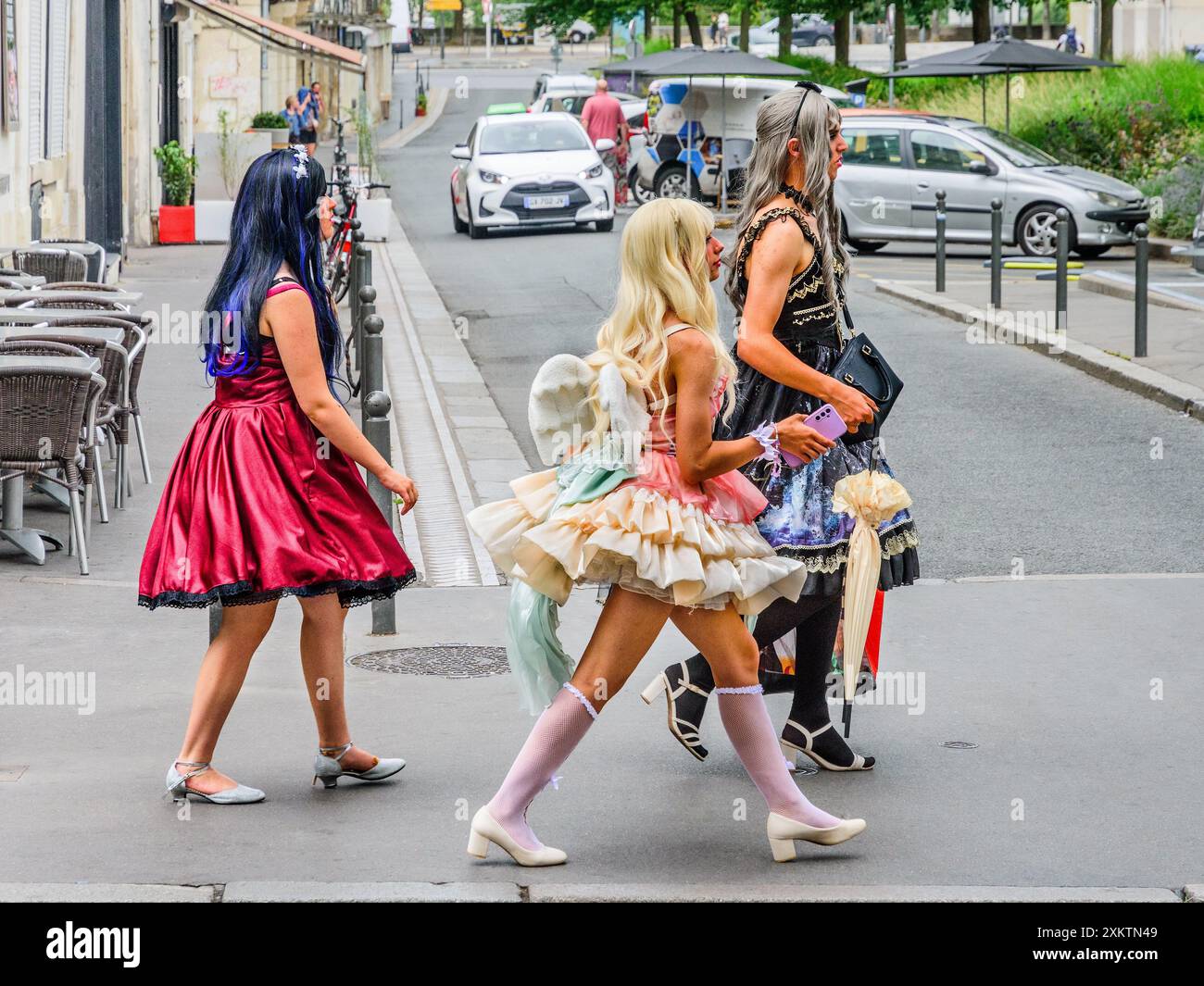 Trois jeunes femmes (ou travestis / hommes en drag / femme à marier) en robe fantaisie marchant à travers la ville - Tours, Indre-et-Loire (37), France. Banque D'Images