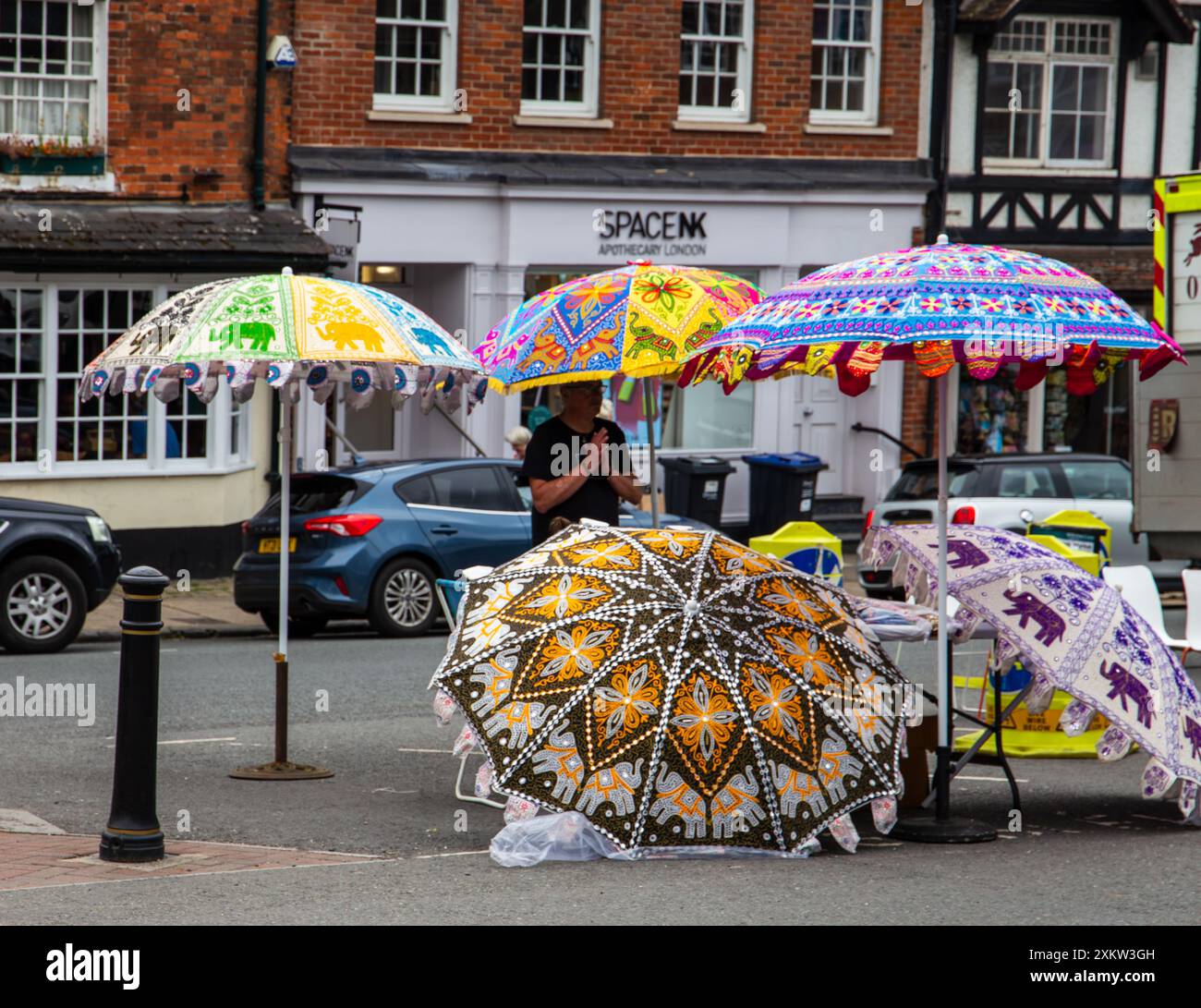 Vendeur de rue vendant des parapluies colorés avec des dessins complexes sur une rue de ville animée. Jour de marché Marlborough Wiltshire Banque D'Images