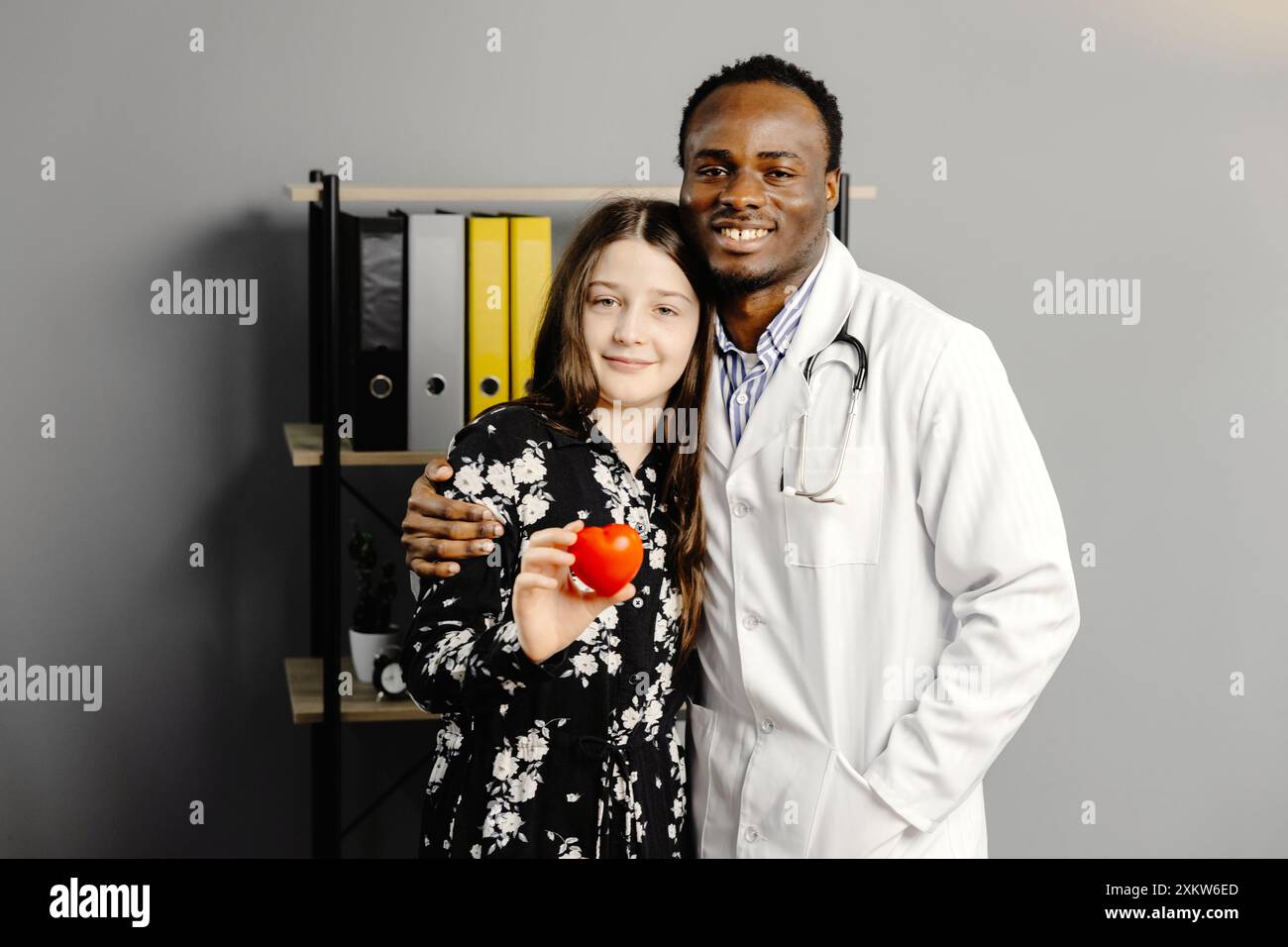 Homme en robe blanche et fille debout ensemble, fille tenant le coeur rouge. Banque D'Images