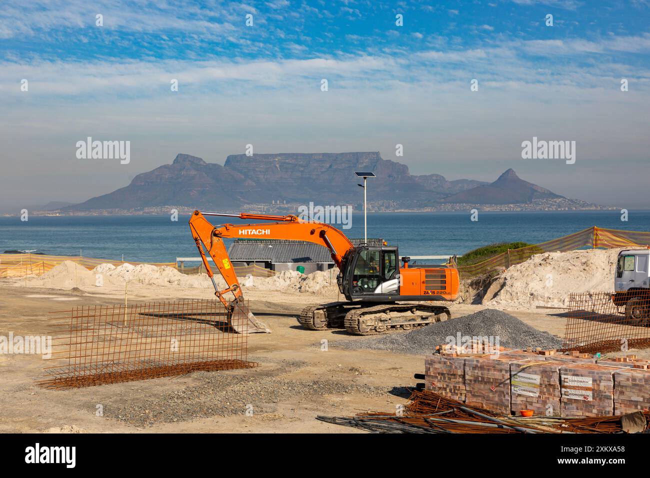 Excavatrice sur chenilles Hitachi sur un chantier municipal à Bloubergstrand au Cap. Divers autres matériaux de construction peuvent être vus. Banque D'Images
