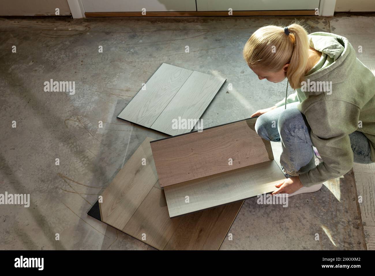 Décorateur d'intérieur détient des échantillons de bois de vinyle de luxe sur le plancher de béton dans le condo. Sélection de revêtements de sol imperméables. Reconstruction de la maison. Carreaux de vinyle Banque D'Images