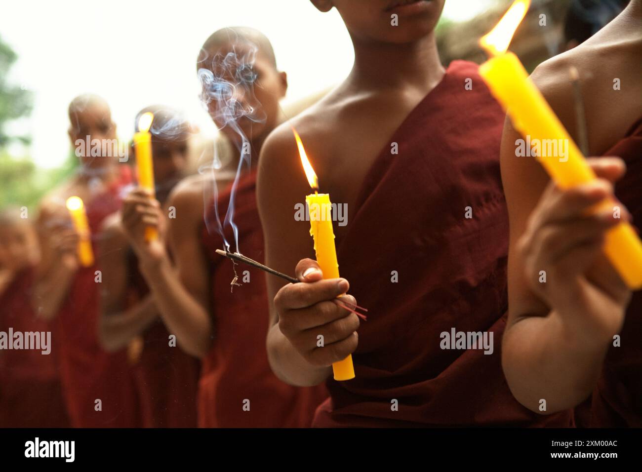 Les enfants moines tiennent des bougies, alors qu'ils font la queue pour prier au temple Mahabodhi à Bodhgaya, Bihar, Inde. Banque D'Images