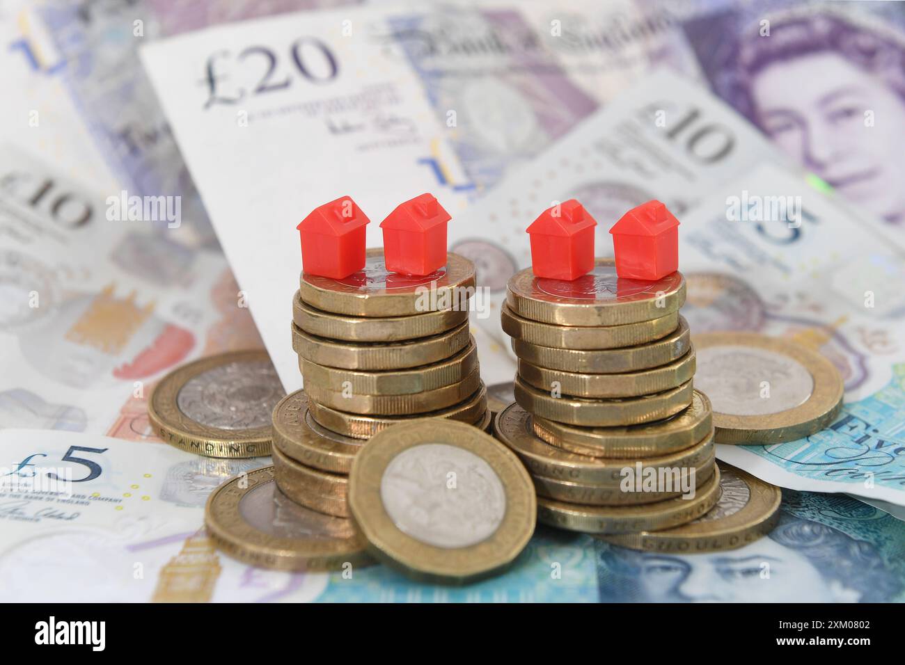 Dossier photo datée du 12/09/18 de maisons modèles sur une pile de pièces et de billets de banque. Les hausses des taux hypothécaires ont plongé environ 320 000 personnes de plus dans la pauvreté à la fin de décembre 2023, selon l’Institut d’études fiscales (IFS). Date d'émission : jeudi 25 juillet 2024. Banque D'Images
