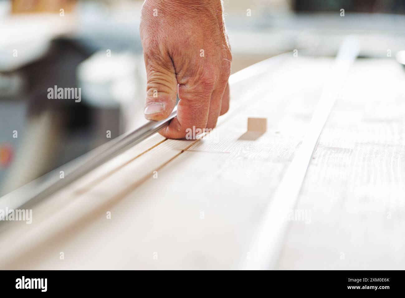 Carpenter utilise soigneusement un ciseau pour façonner une planche de bois dans son atelier, démontrant précision et savoir-faire Banque D'Images