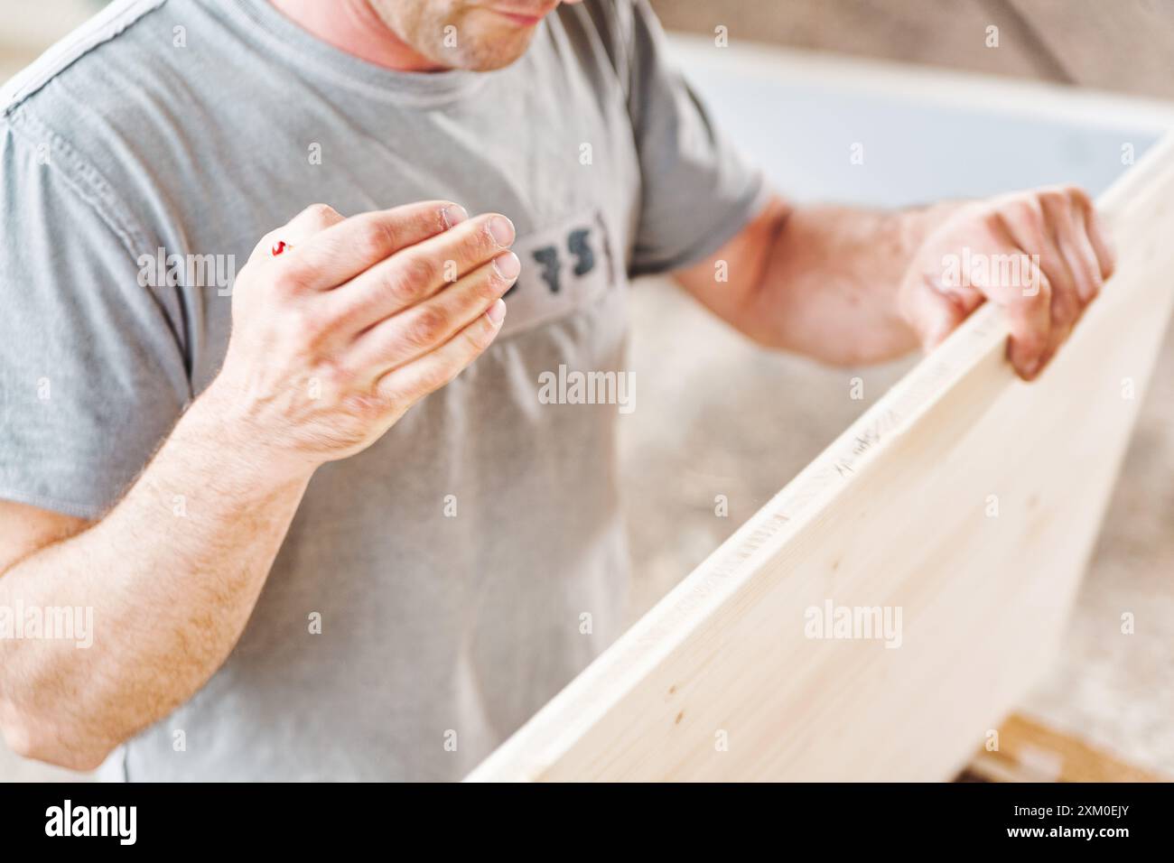 Un charpentier caucasien en détresse examine son doigt saignant dans un atelier dangereux, soulignant le danger de son travail qualifié dans la construction Banque D'Images