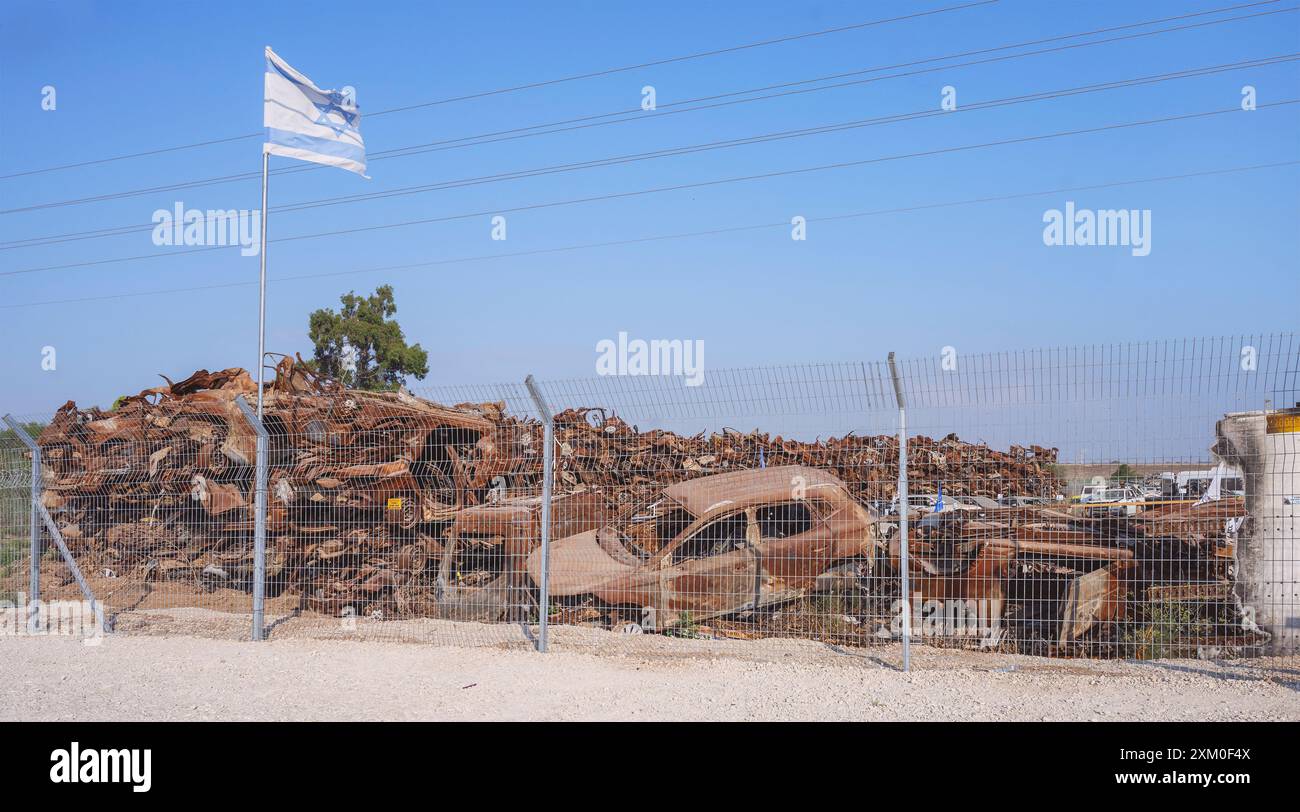 Le drapeau israélien survole une petite partie des véhicules qui ont été attaqués et incendiés le 7 octobre dans la zone frontalière de l'enveloppe de Gaza avec un ciel bleu BA Banque D'Images