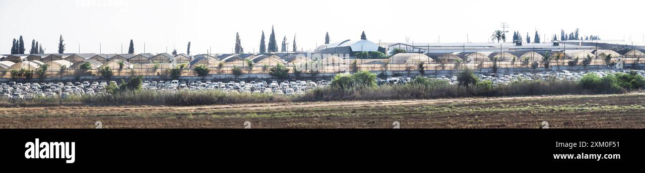 Une petite section des rangées et des rangées de voitures détruites par l'invasion d'Israël par le Hamas le 7 octobre avec un ciel dégagé et des terres agricoles Banque D'Images