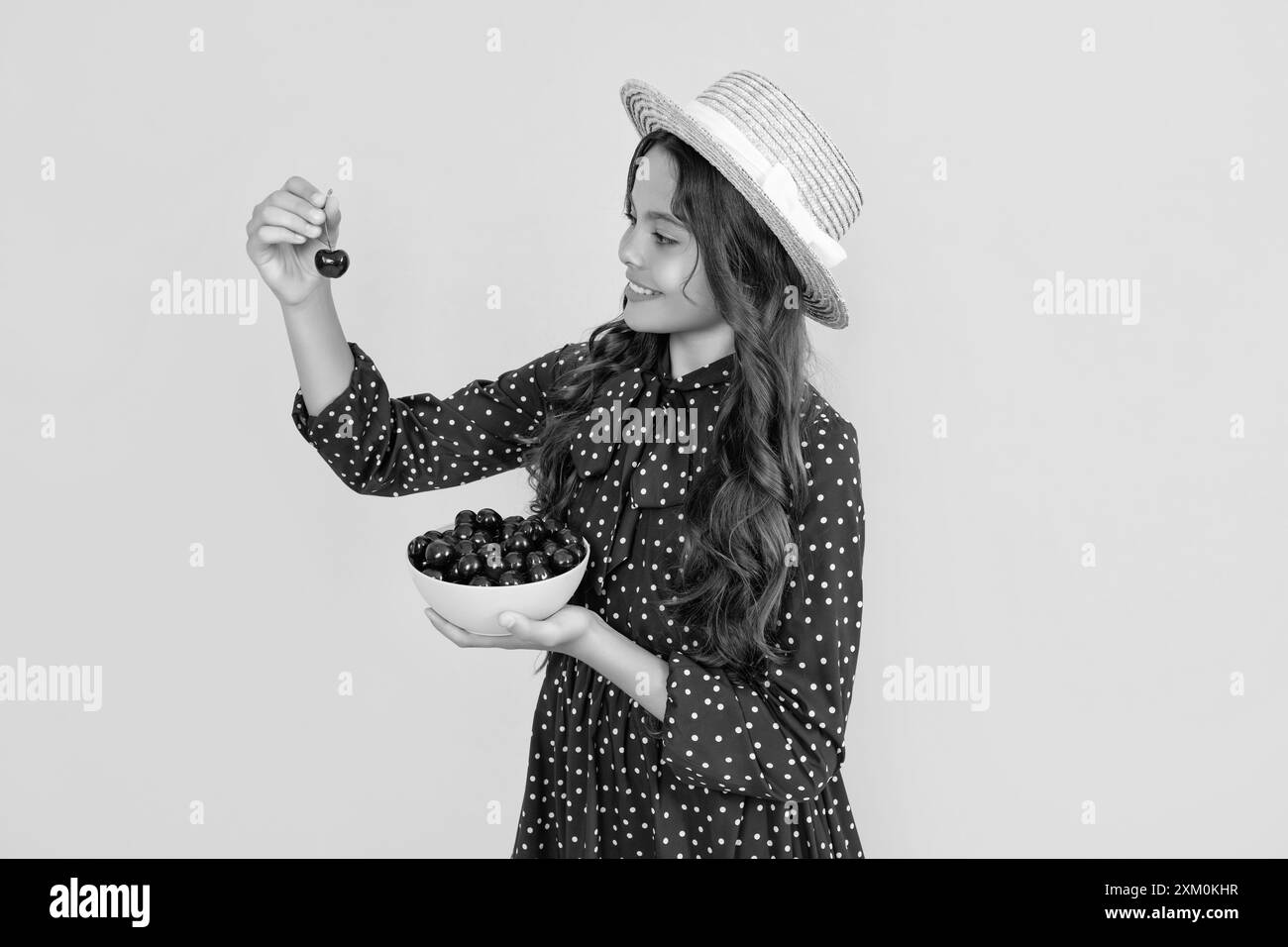 un adolescent positif mange un bol de cerise sur fond jaune Banque D'Images