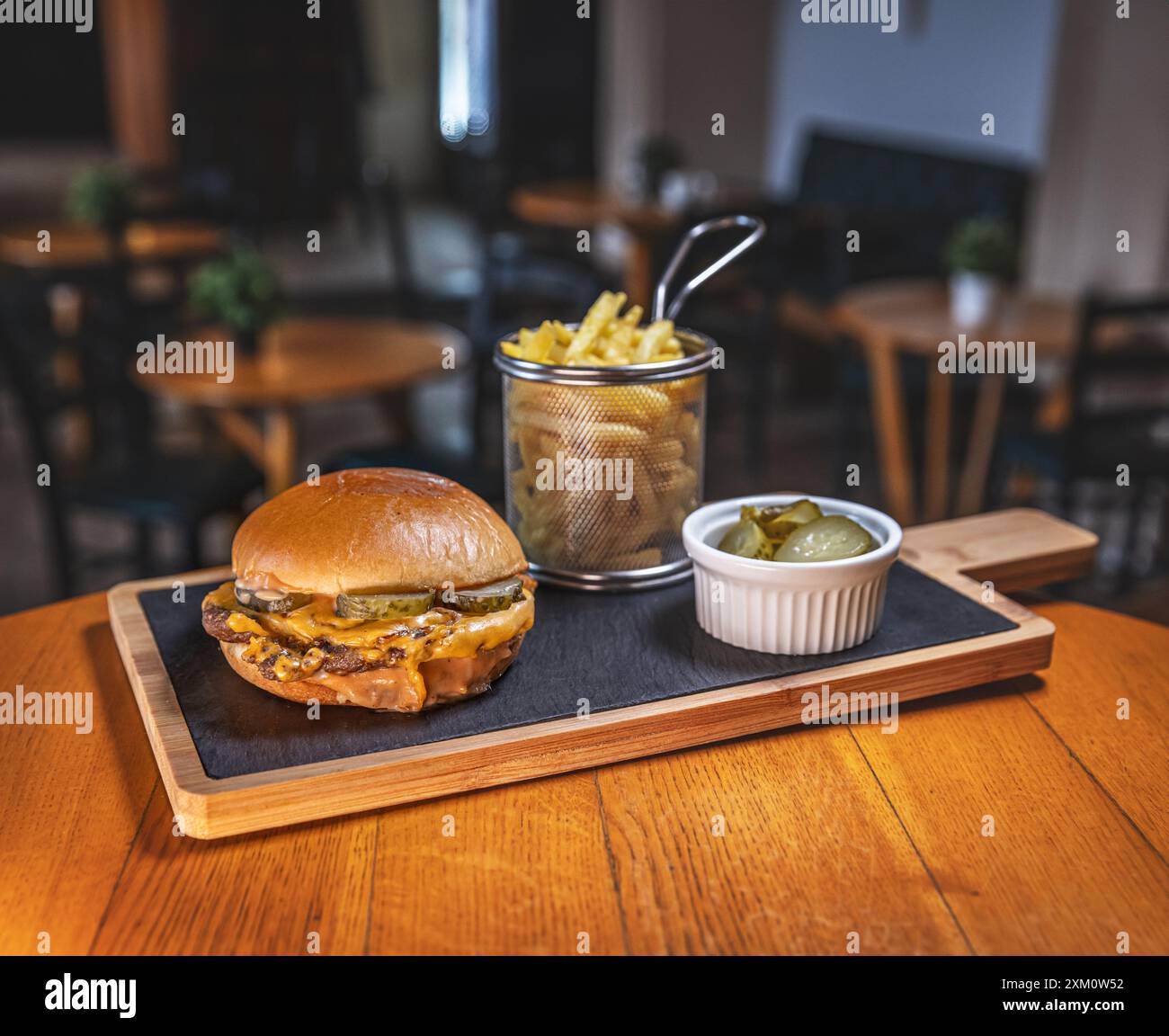 Cheeseburger fraîchement préparé avec frites et cornichons servis dans un restaurant Banque D'Images
