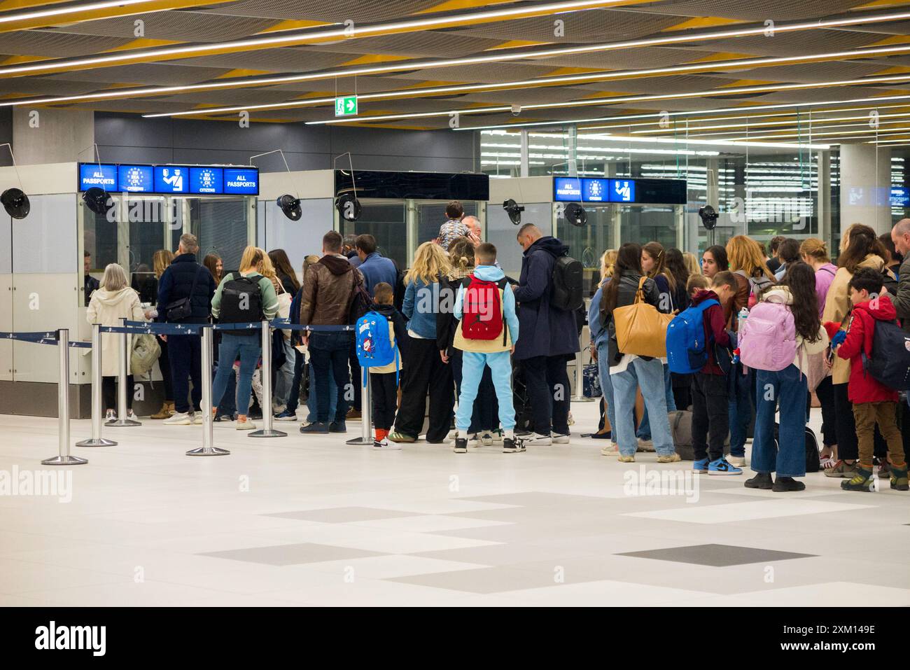 Les passagers arrivant, principalement des touristes en vacances, font la queue aux arrivées pour parler aux fonctionnaires aux portes d'immigration de contrôle des passeports. Aéroport de Split, Croatie. (138) Banque D'Images