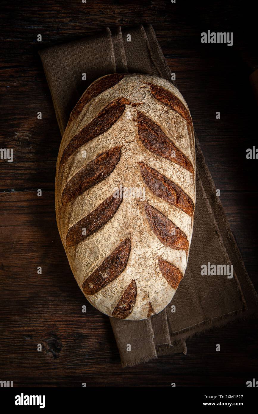 Pain au levain. Pain de blé biologique fraîchement cuit sur un fond sombre, avec nappe de lin. Vue de dessus, espace de copie. Banque D'Images