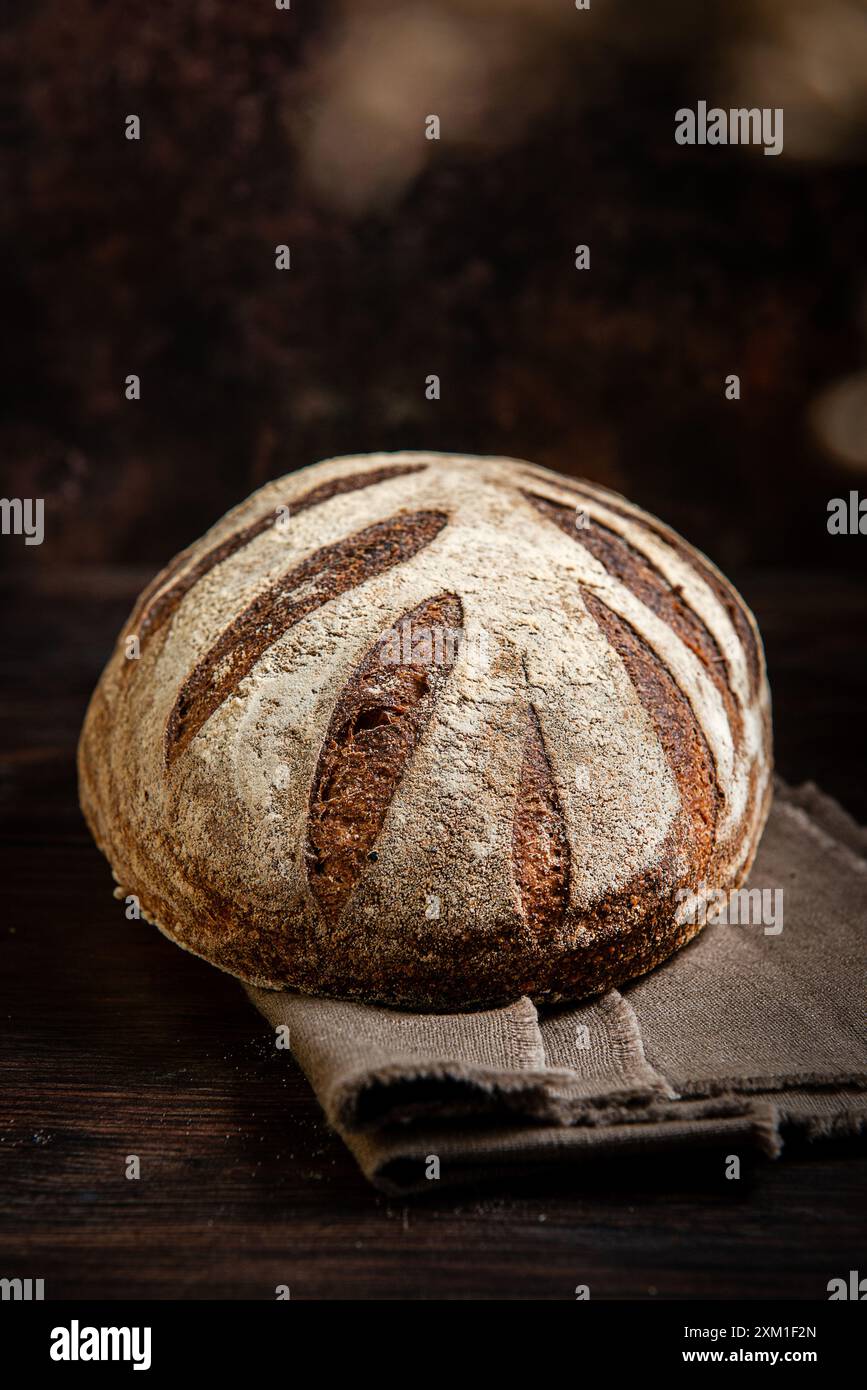 Pain au levain. Pain de blé biologique fraîchement cuit sur un fond sombre, avec nappe de lin. Vue de dessus, espace de copie. Banque D'Images