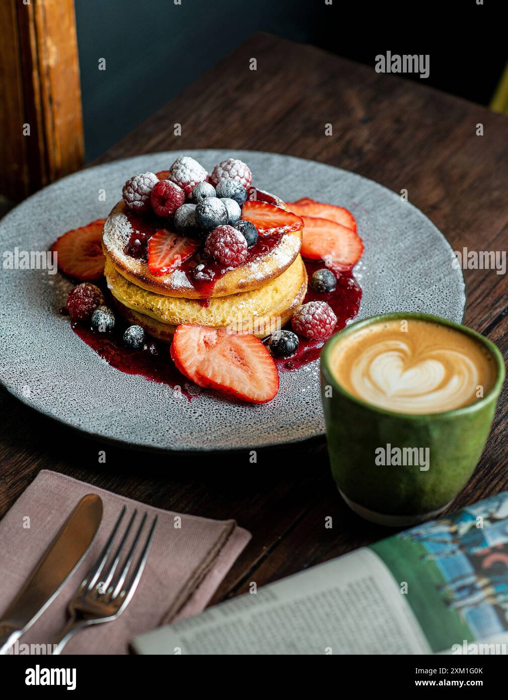 Crêpe moelleuse maison avec des fruits et de la confiture sur le dessus avec une tasse de cappuccino. Banque D'Images