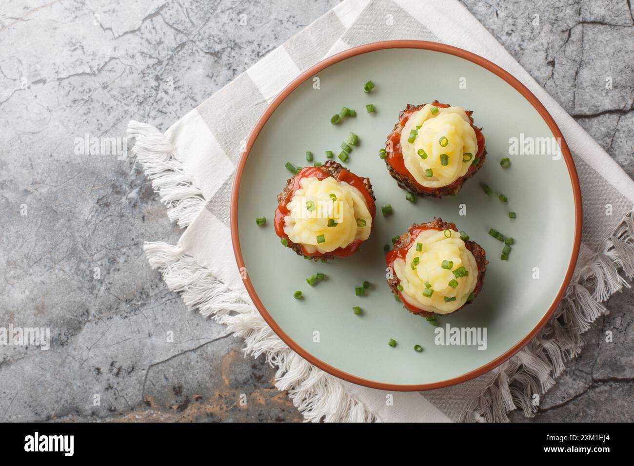 Muffins de pain de viande de bœuf avec sauce tomate et purée de pommes de terre gros plan dans une assiette sur la table. Idée pour une table de buffet. Vue horizontale de dessus Banque D'Images