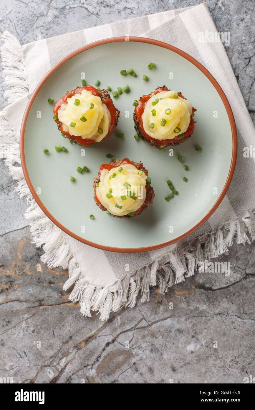 Cupcakes de pain de viande avec sauce tomate et purée de pommes de terre sur le dessus gros plan dans une assiette sur la table. Vue de dessus verticale Banque D'Images