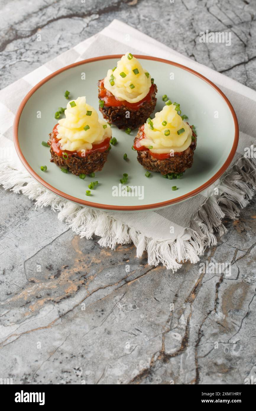 Cupcakes de pain de viande avec sauce tomate et purée de pommes de terre sur le dessus gros plan dans une assiette sur la table. Vertical Banque D'Images
