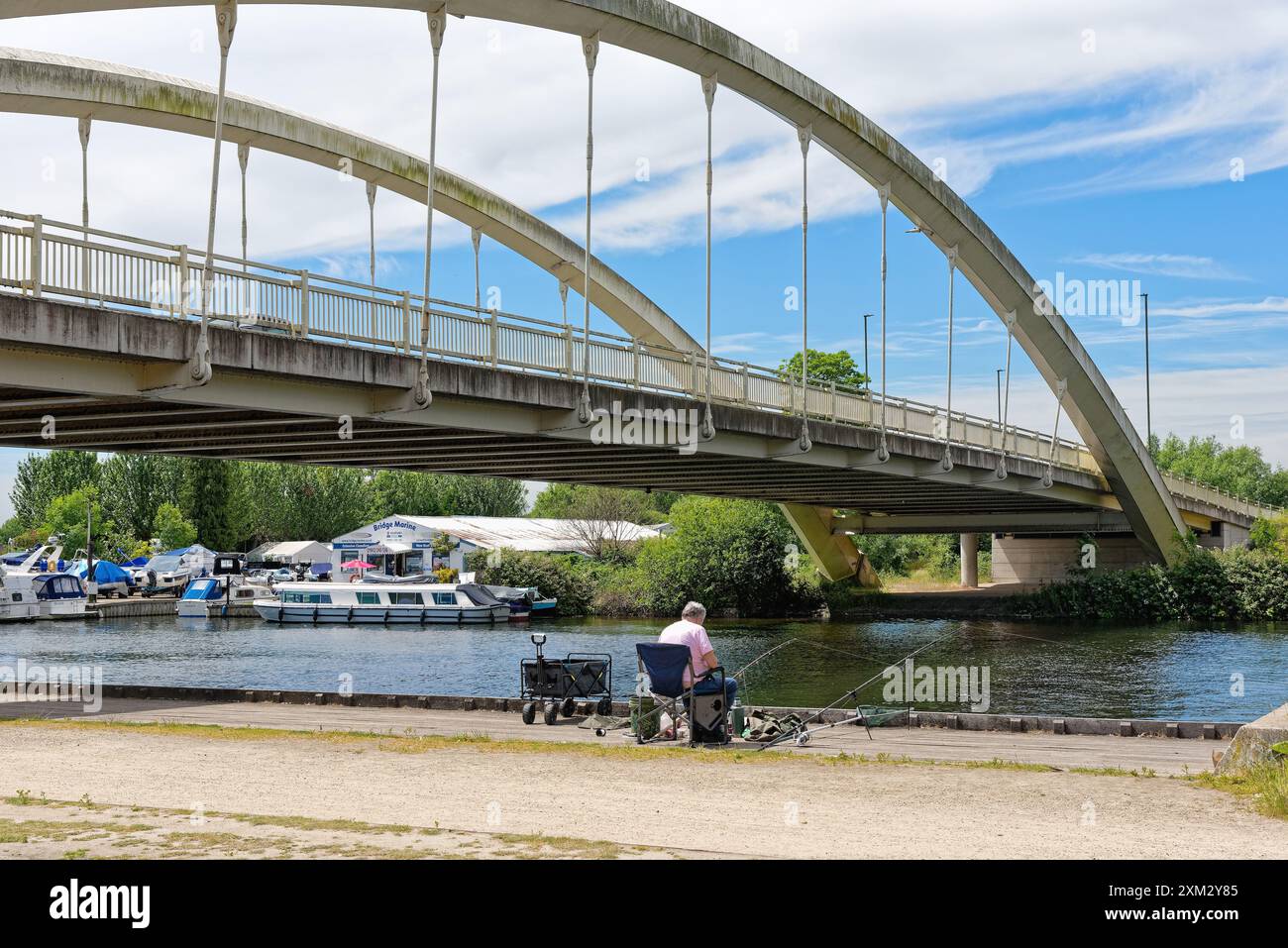 Un homme âgé moyen pêchant dans la Tamise à côté du pont Walton lors d'une journée ensoleillée d'été Surrey Angleterre Royaume-Uni Banque D'Images