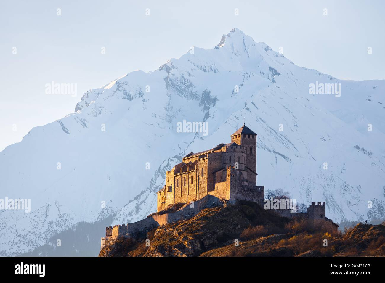 Vue paysagère hivernale de la basilique Valère illuminée à l'heure dorée devant une montagne enneigée, prise à Sion Wallis Suisse Banque D'Images