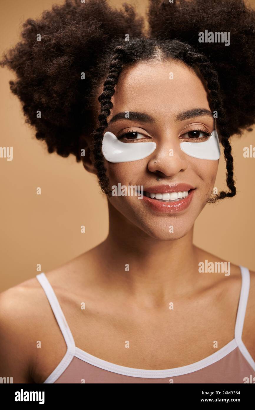 Une jeune femme afro-américaine avec un sourire radieux et des plaques oculaires, mettant en valeur la diversité dans la beauté. Banque D'Images