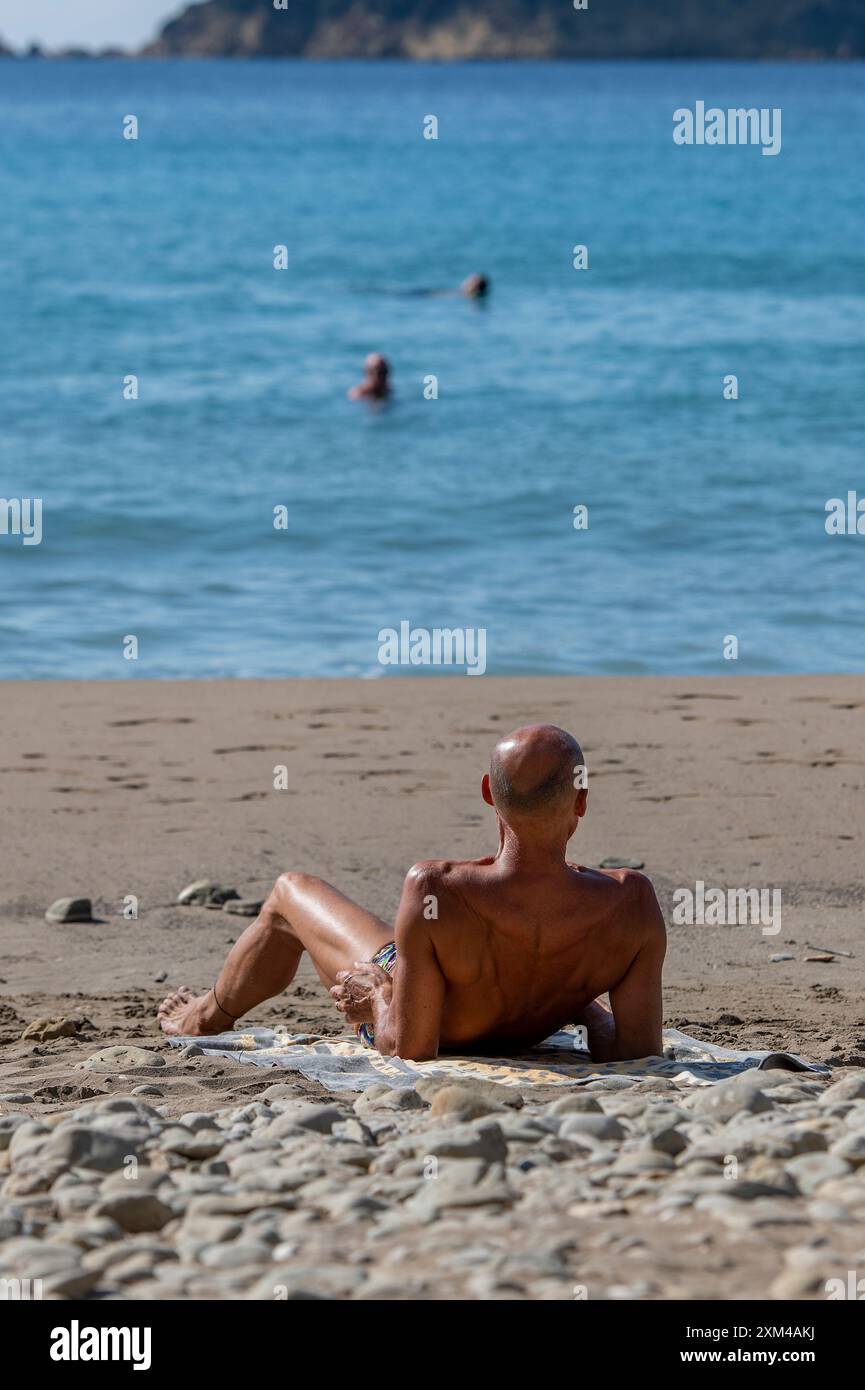 homme âgé d'âge moyen bronzant sur une plage méditerranéenne Banque D'Images