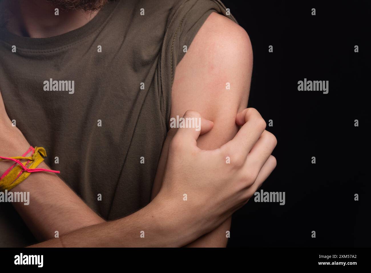 Homme se grattant l'épaule avec sa main. Maladie de la peau. Irritation, allergie. Isolé sur fond noir. Banque D'Images