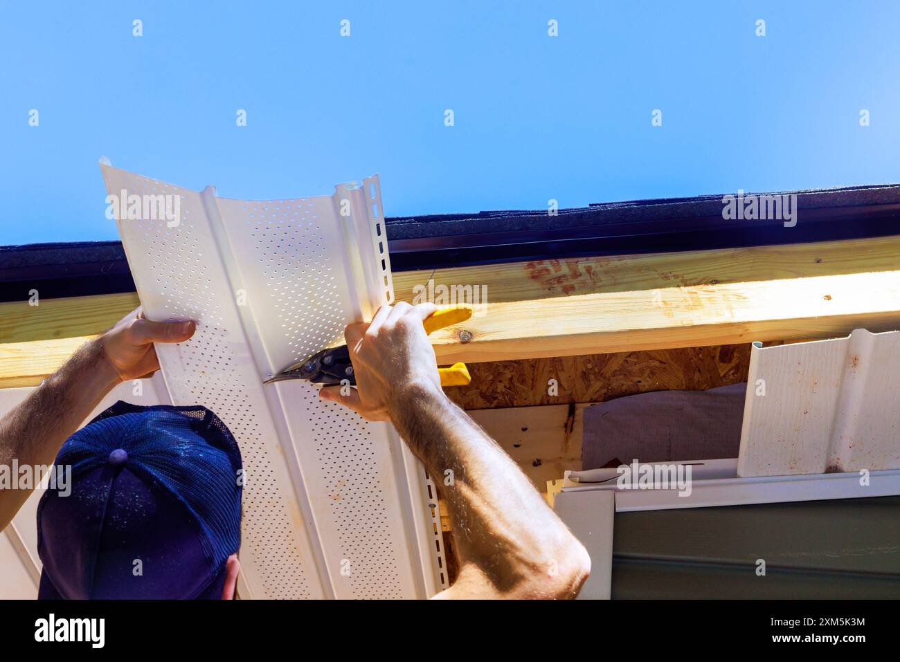 Incorporation de panneaux en plastique de soffite de vinyle dans le plafond de façade d'une nouvelle maison par un employé Banque D'Images