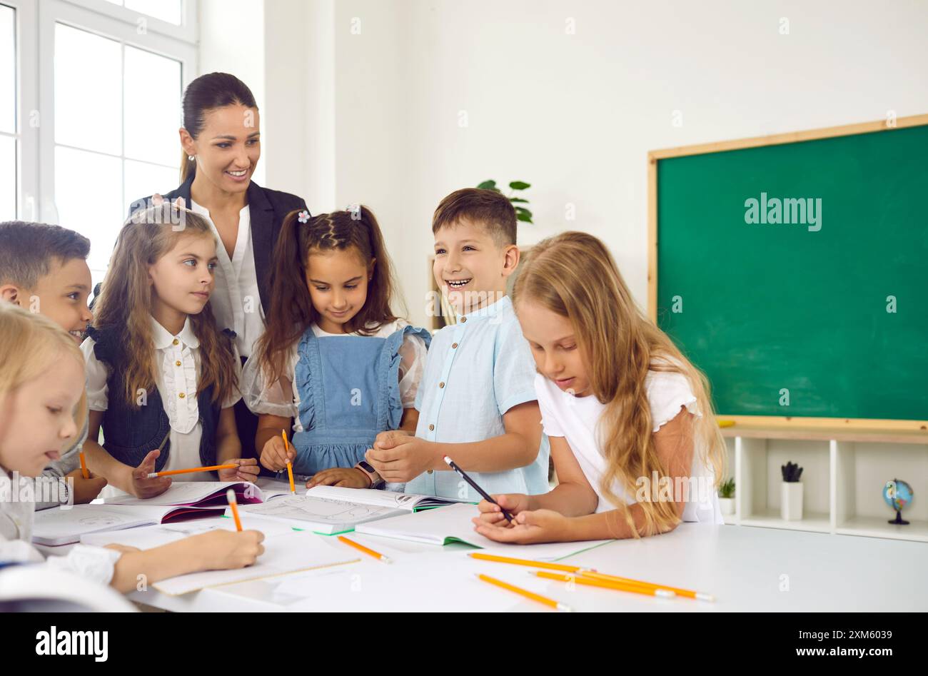 Amicale enseignante souriante est heureuse d'enseigner des leçons amusantes aux enfants à l'école primaire. Banque D'Images