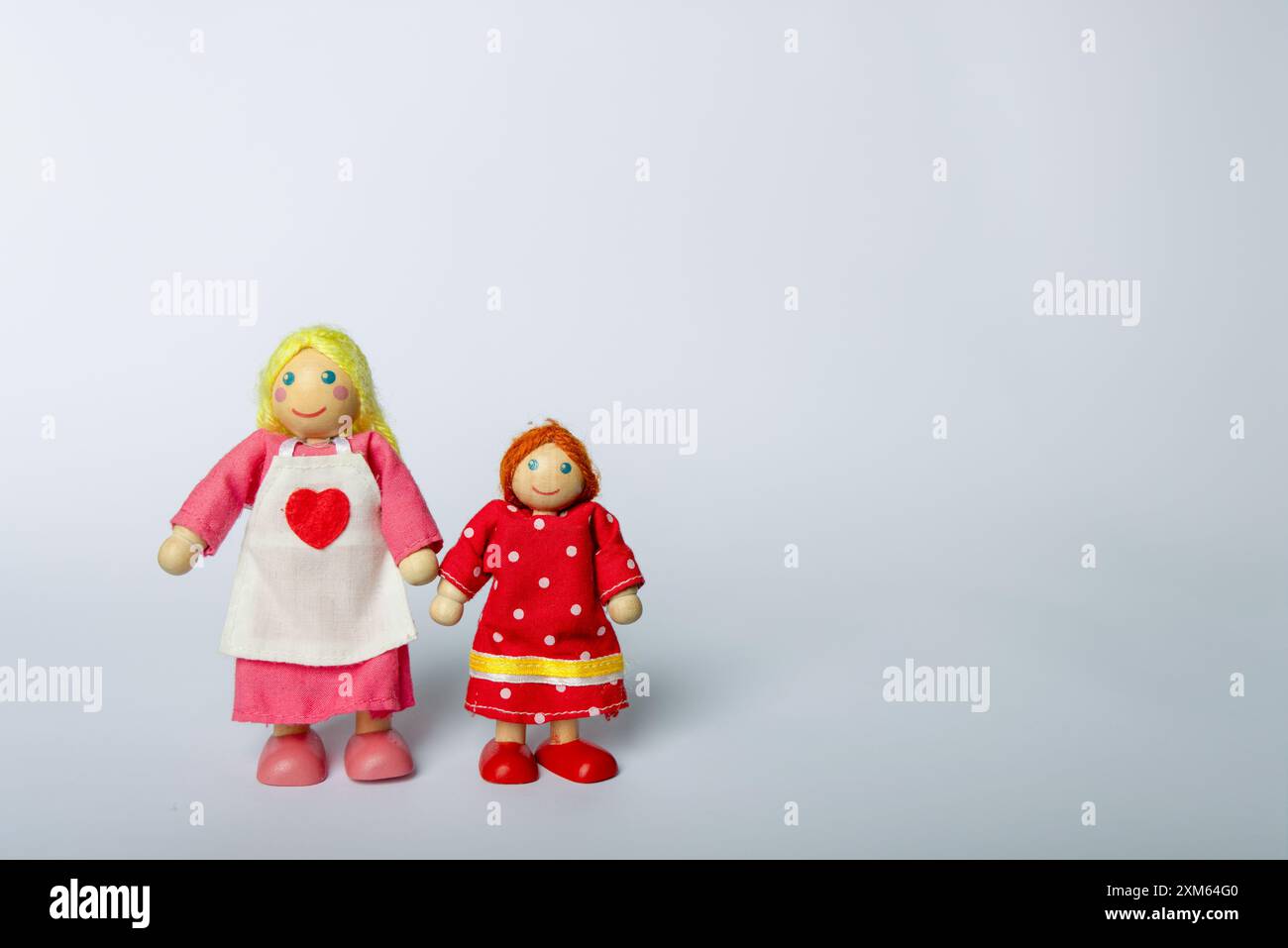 Jouets en bois représentant une mère et une fille tenant la main sur un fond blanc. Une représentation simple et sincère de l'amour maternel Banque D'Images