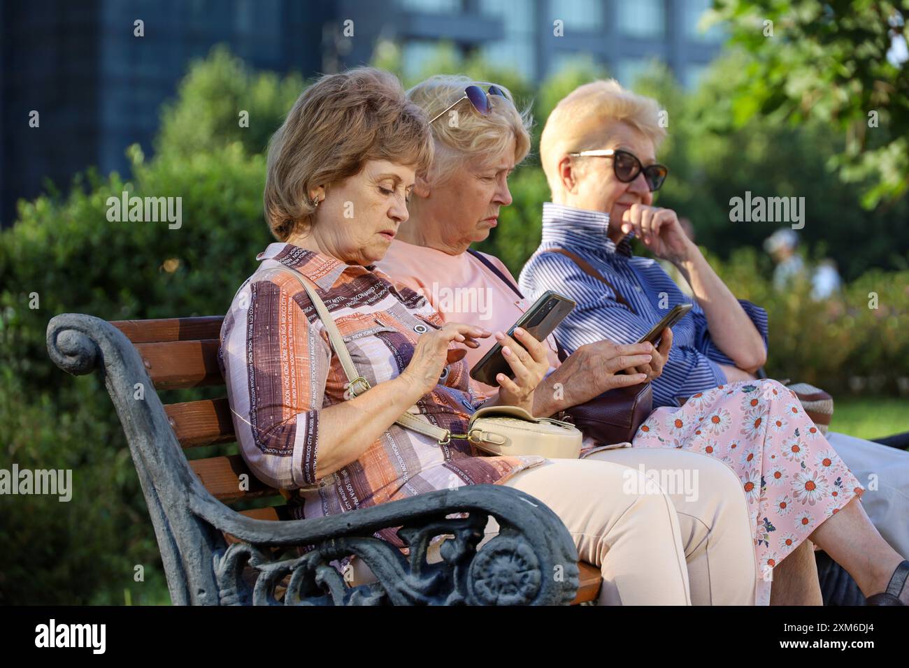 Femmes âgées assis sur la rue de la ville d'été avec des smartphones dans les mains Banque D'Images