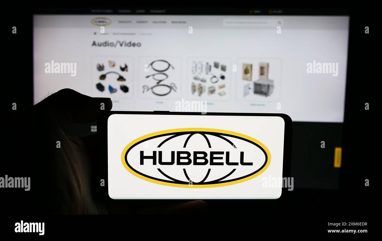 Personne tenant le téléphone portable avec le logo de la société d'électronique américaine Hubbell Incorporated devant la page Web de l'entreprise. Concentrez-vous sur l'affichage du téléphone. Banque D'Images