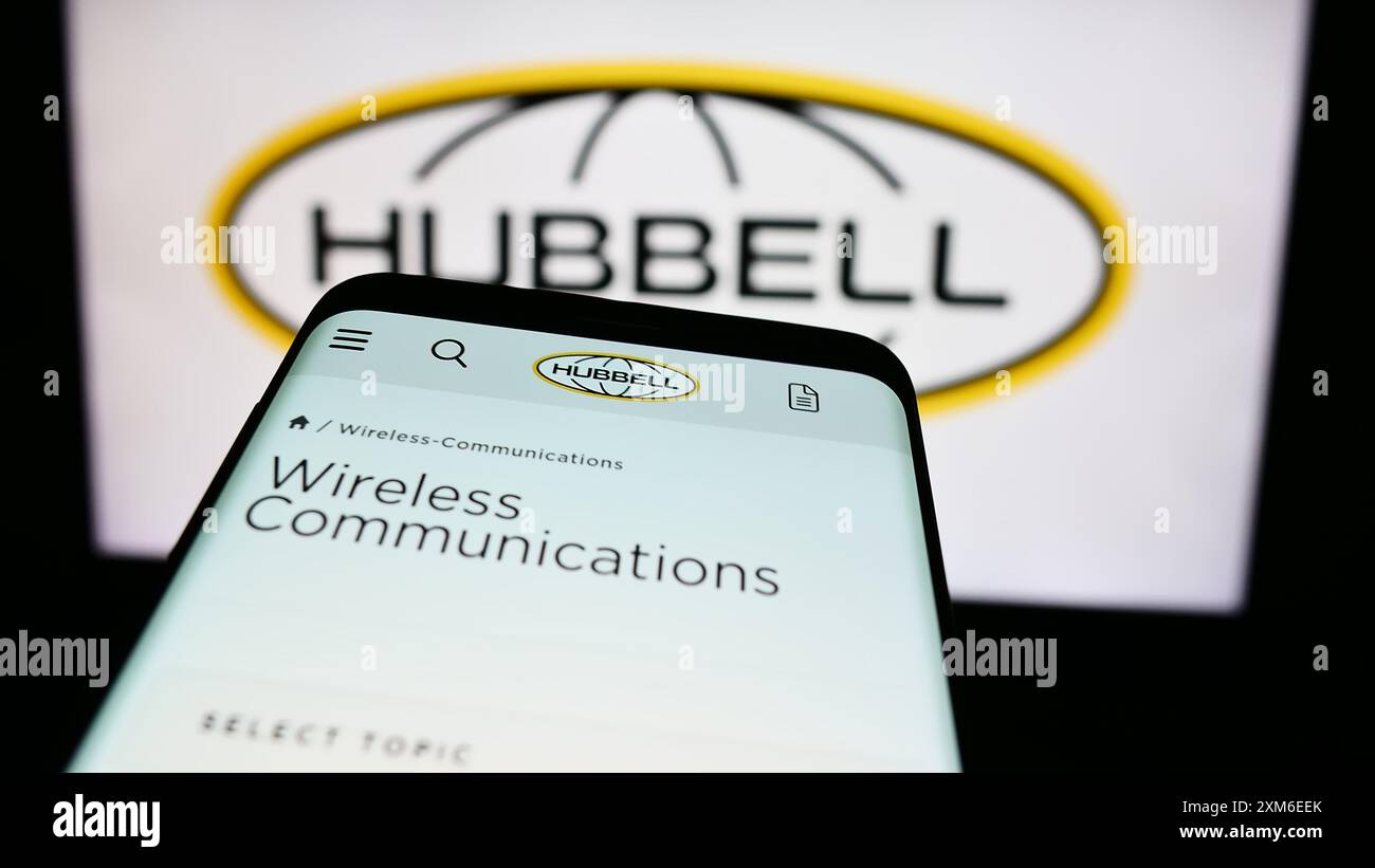 Téléphone portable avec site Web de la société d'électronique américaine Hubbell Incorporated devant le logo de l'entreprise. Concentrez-vous sur le coin supérieur gauche de l'écran du téléphone. Banque D'Images