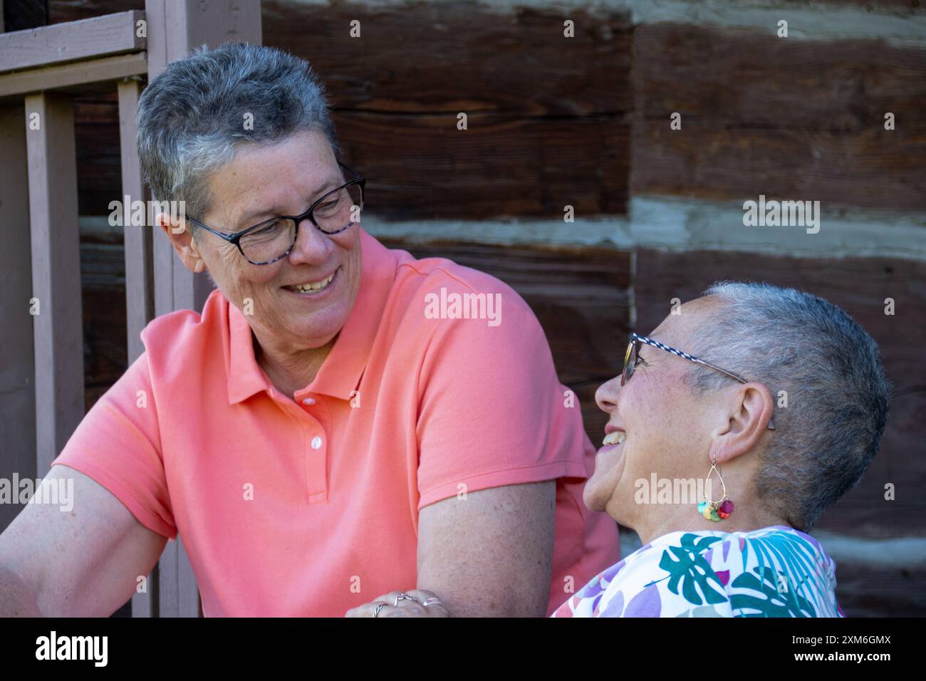 Couple gay plus âgé souriant et discutant sur le porche Banque D'Images