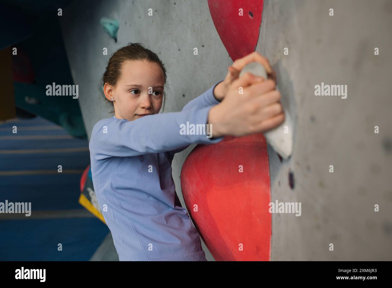 portrait d'une fille grimpant dans un centre d'escalade intérieur Banque D'Images