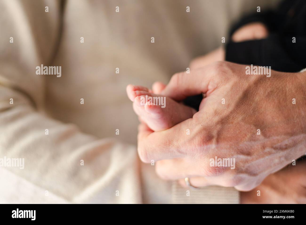 Gros plan des mains tenant doucement le petit pied d'un nouveau-né. Banque D'Images
