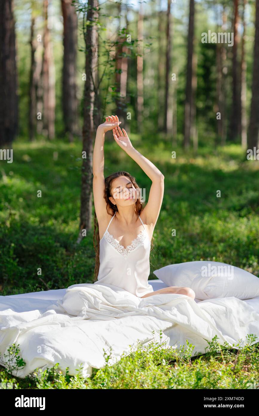 Femme dort sur un matelas dans la forêt d'été. Fille se réveille dans une forêt d'été Banque D'Images