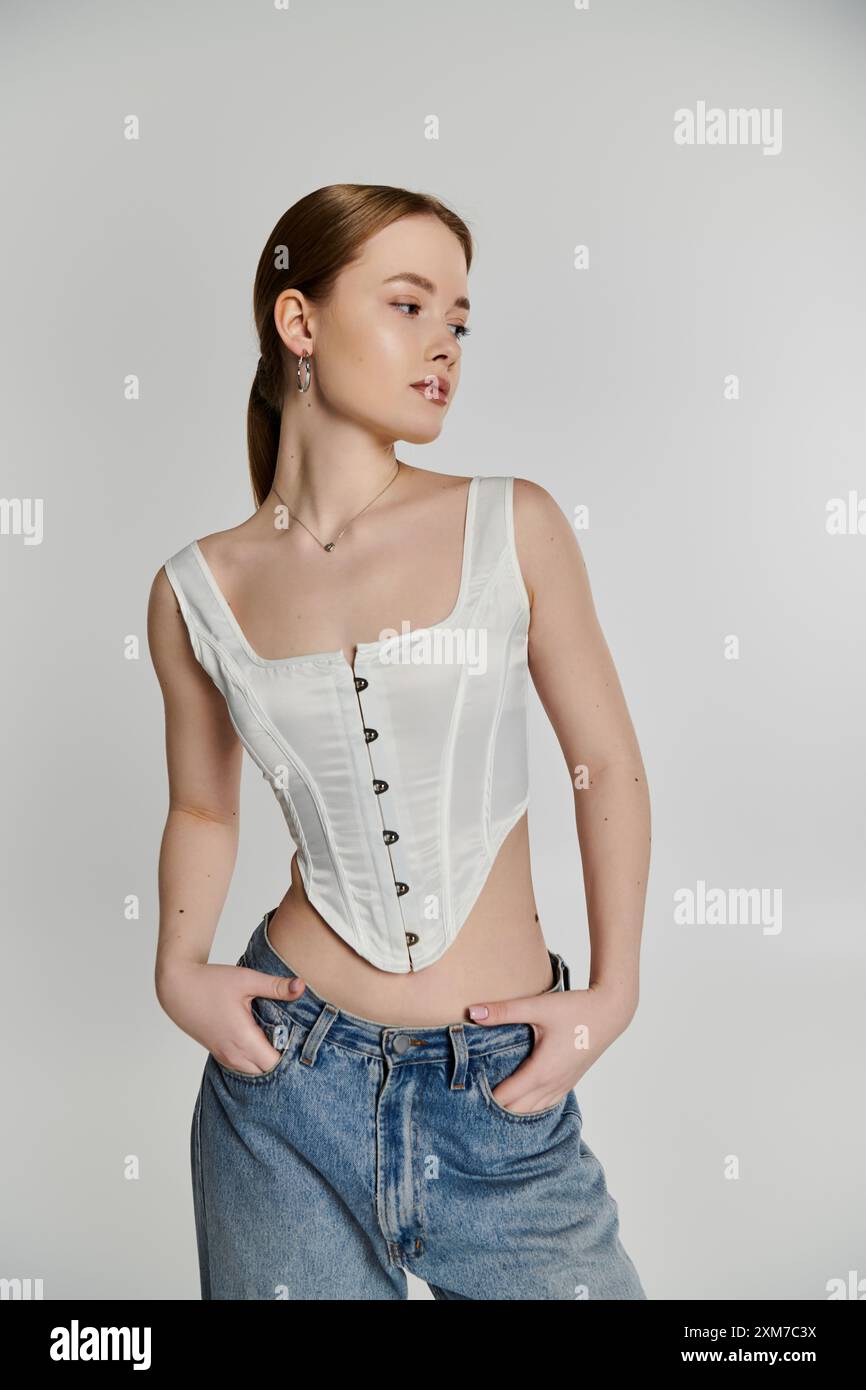 Une jeune femme pose en toute confiance dans un corset blanc, rayonnant d'élégance et de style moderne. Banque D'Images