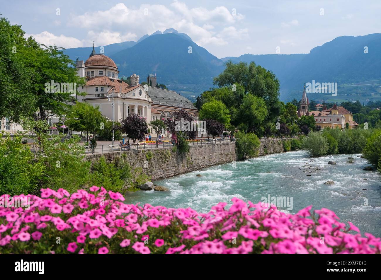 Merano, Tyrol du Sud, Italie - Kurhaus sur la rivière passer, sur la promenade de passer dans le vieux centre-ville. Fleurs roses devant sur le pont thermique. Banque D'Images