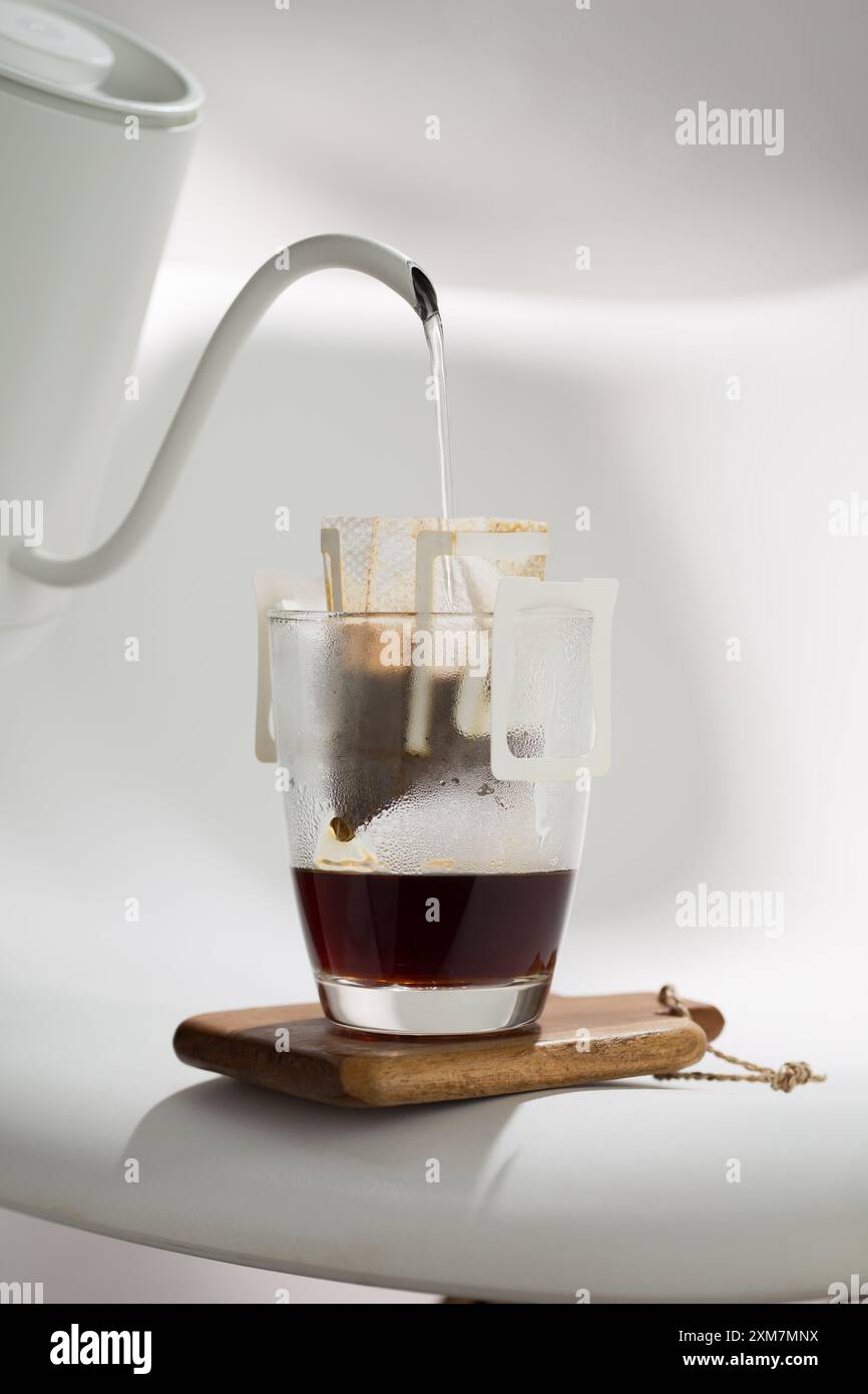 Un sac d'égouttement filtre méthodiquement l'eau à travers le Marc de café, illustrant la précision des techniques de préparation. Banque D'Images