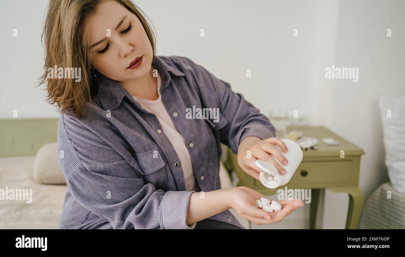 Femme versant des pilules blanches dans la main à partir de la bouteille. Plus taille fille va prendre des pilules de régime, pour perdre du poids. Problèmes des personnes souffrant d'insuffisance pondérale et d'acceptation de soi. Banque D'Images