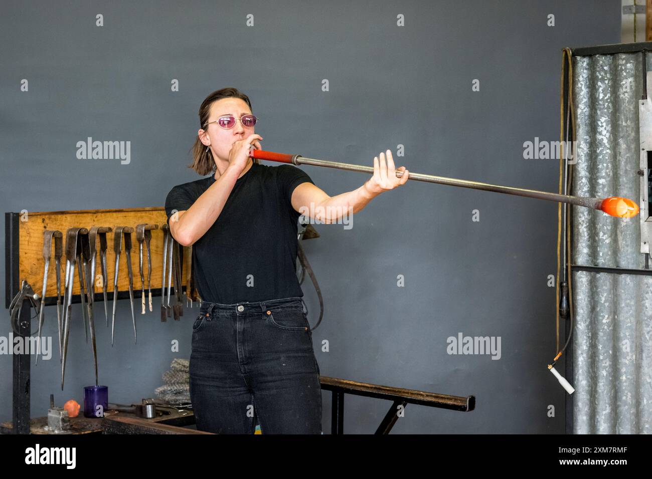 Axelle Mary, artiste française et souffleur de verre, au travail soufflant du verre dans son studio au pays de Galles, au Royaume-Uni Banque D'Images