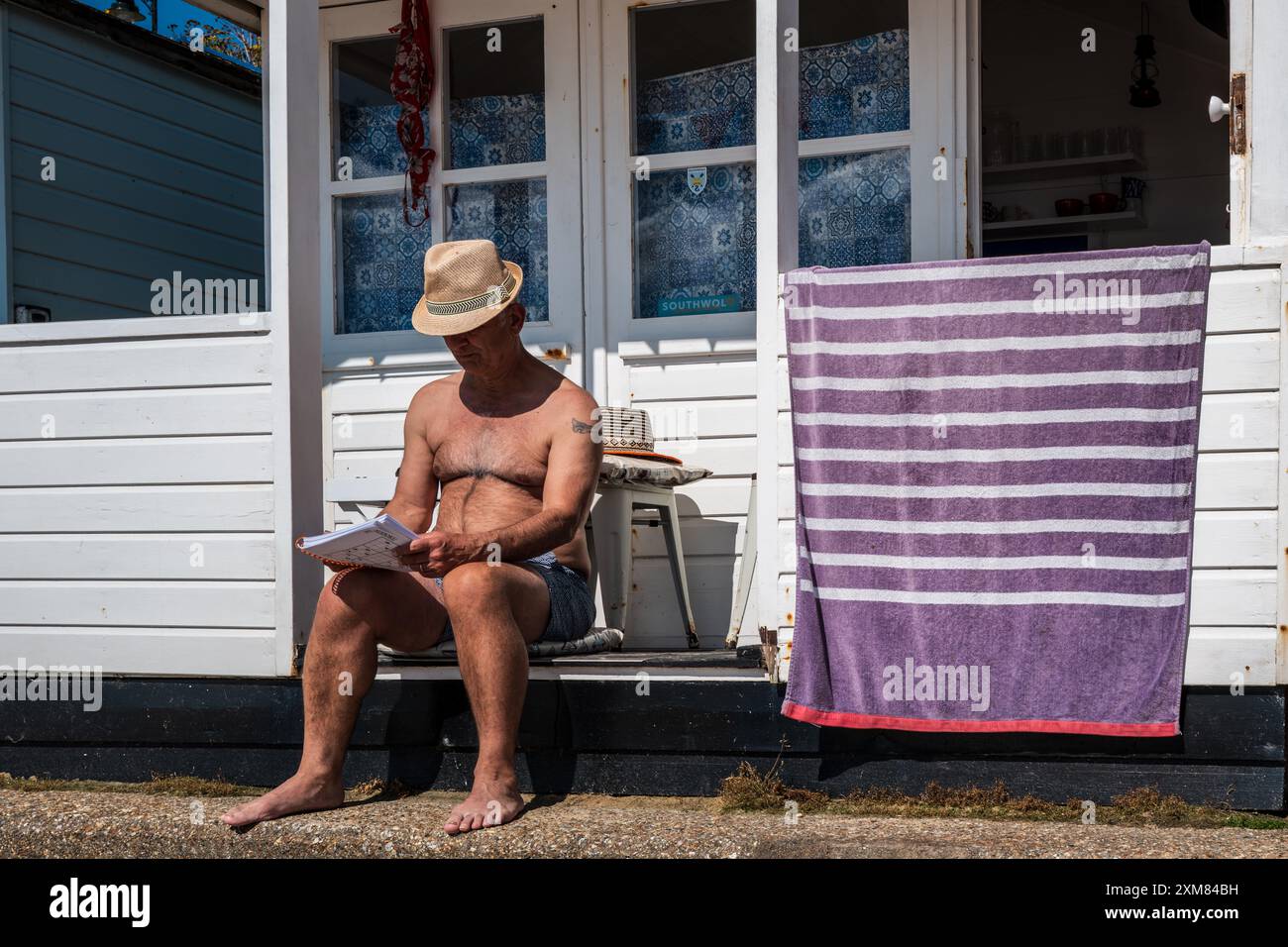 Couple buvant un cocktail assis à l'extérieur d'une cabane de plage à Southwold, Suffolk, Royaume-Uni. Concept vacances, été anglais, vacances anglais, bord de mer. Banque D'Images