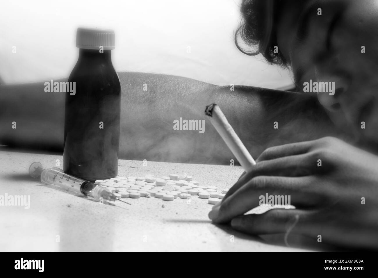 homme sans le savoir toxicomane, consommant des cigarettes de marijuana ou de l'ecstasy de drogue, overdose de drogue dure et concept de dépendance, photo noir et blanc Banque D'Images