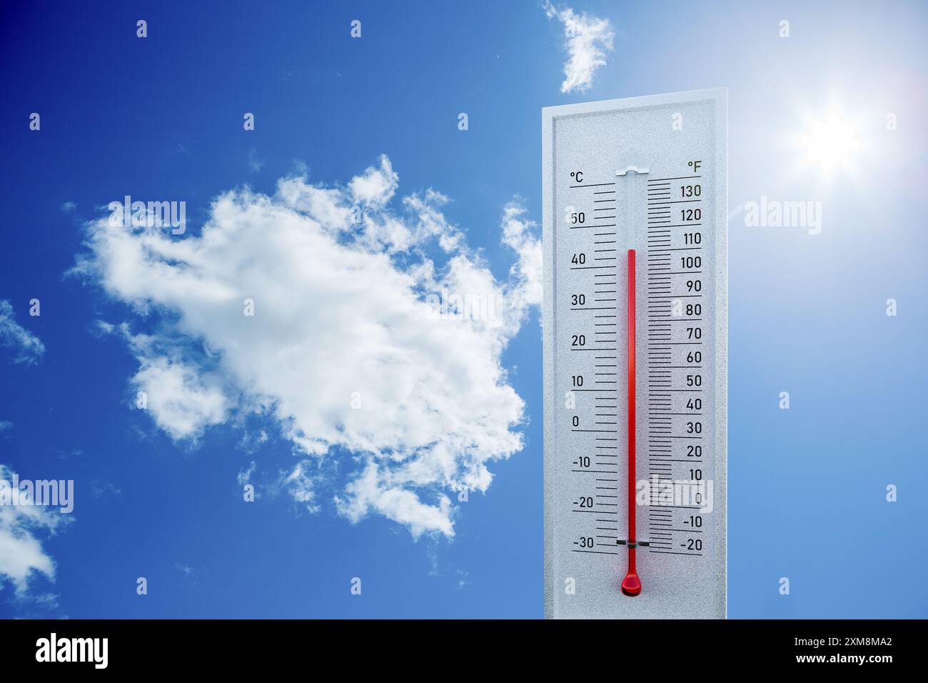 Concept de vague de chaleur : un thermomètre montrant 44° celsius / 110° Fahrenheit devant un ciel bleu avec nuages et soleil direct. Banque D'Images