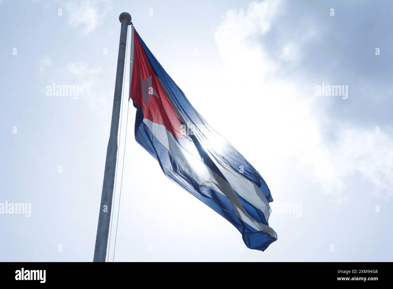 Le drapeau national de Cuba flotte sur un mât de drapeau par une belle journée d'été avec un fond de ciel bleu et de nuages blancs. Banque D'Images