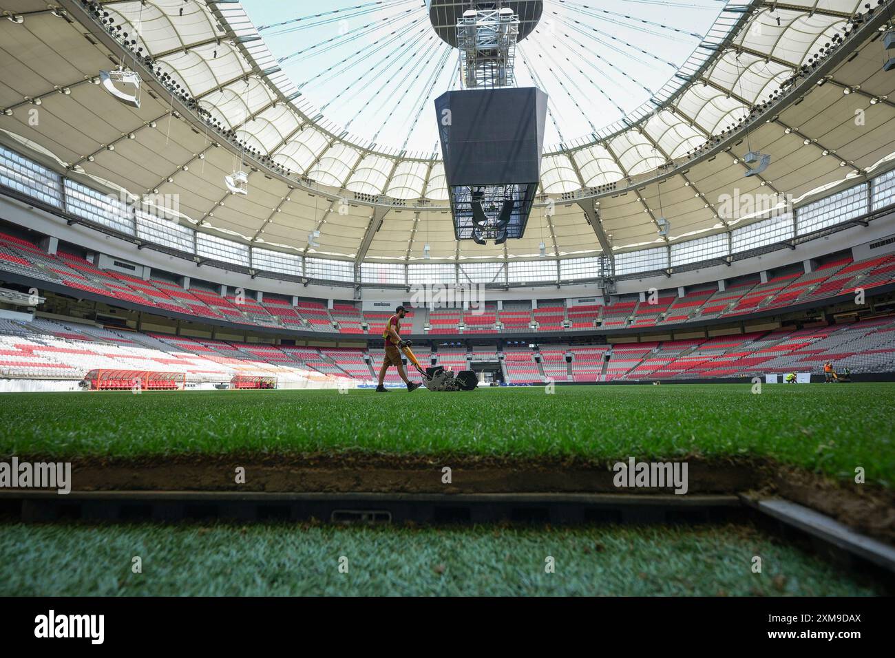 A worker cuts temporary grass that was laid on top of artificial turf at BC Place stadium for an international friendly soccer match between MLS' Vancouver Whitecaps and League One's Wrexham in Vancouver, British Columbia, Friday, July 26, 2024. (Darryl Dyck/The Canadian Press via AP) Banque D'Images