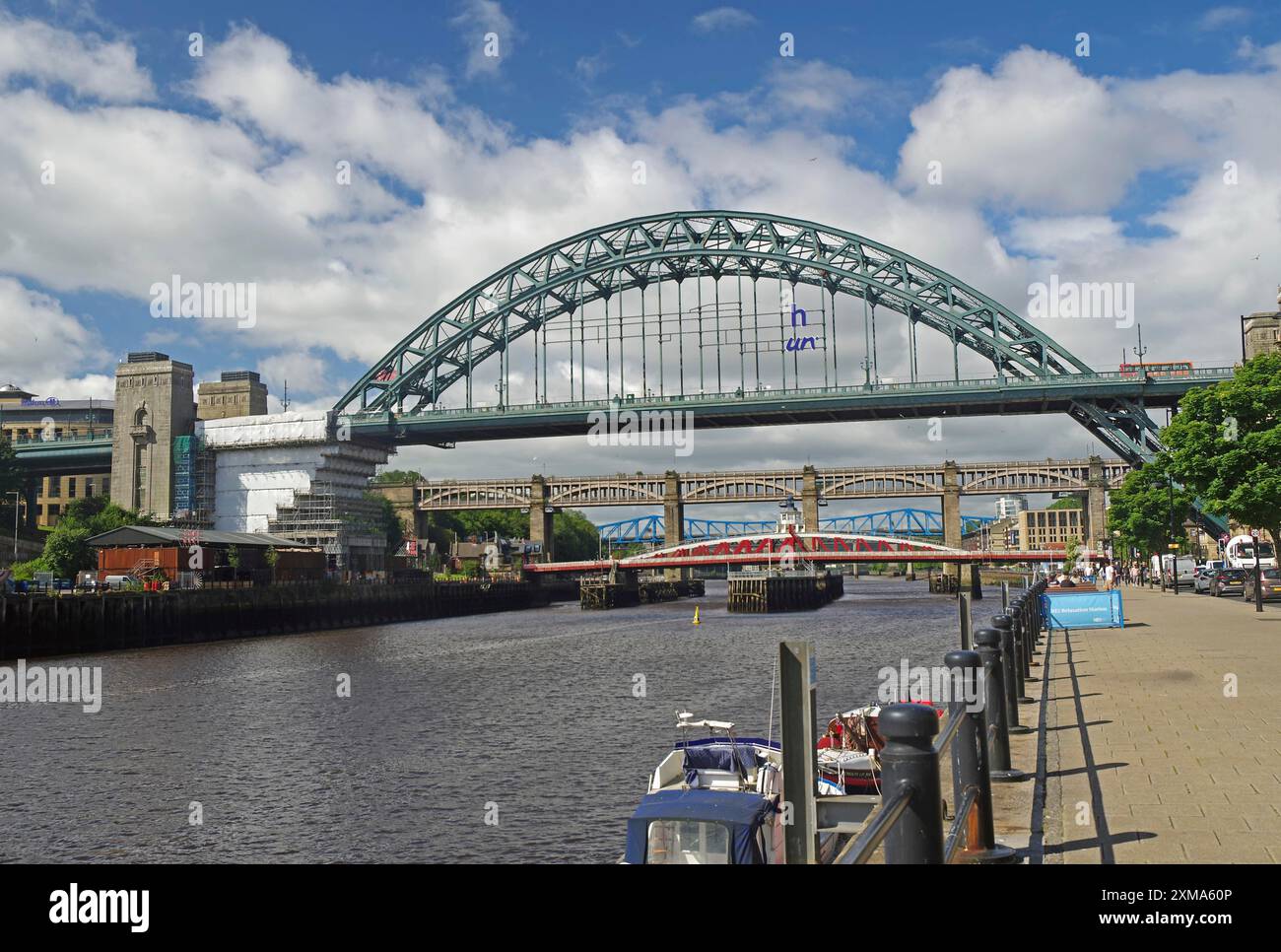 Plusieurs ponts sur une rivière dans une ville, flanqués de bâtiments et de bateaux par une journée ensoleillée sous un ciel bleu avec des nuages, Newcastle, Nord de l'Angleterre Banque D'Images