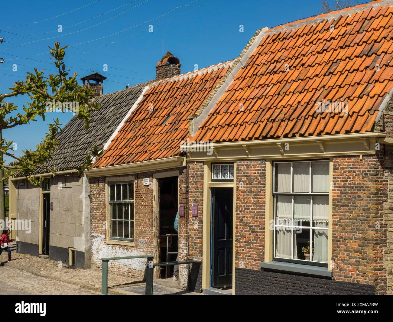 Maisons traditionnelles aux toits en tuiles orange et aux façades variées sous un ciel bleu clair, enkhuizen, pays-bas Banque D'Images