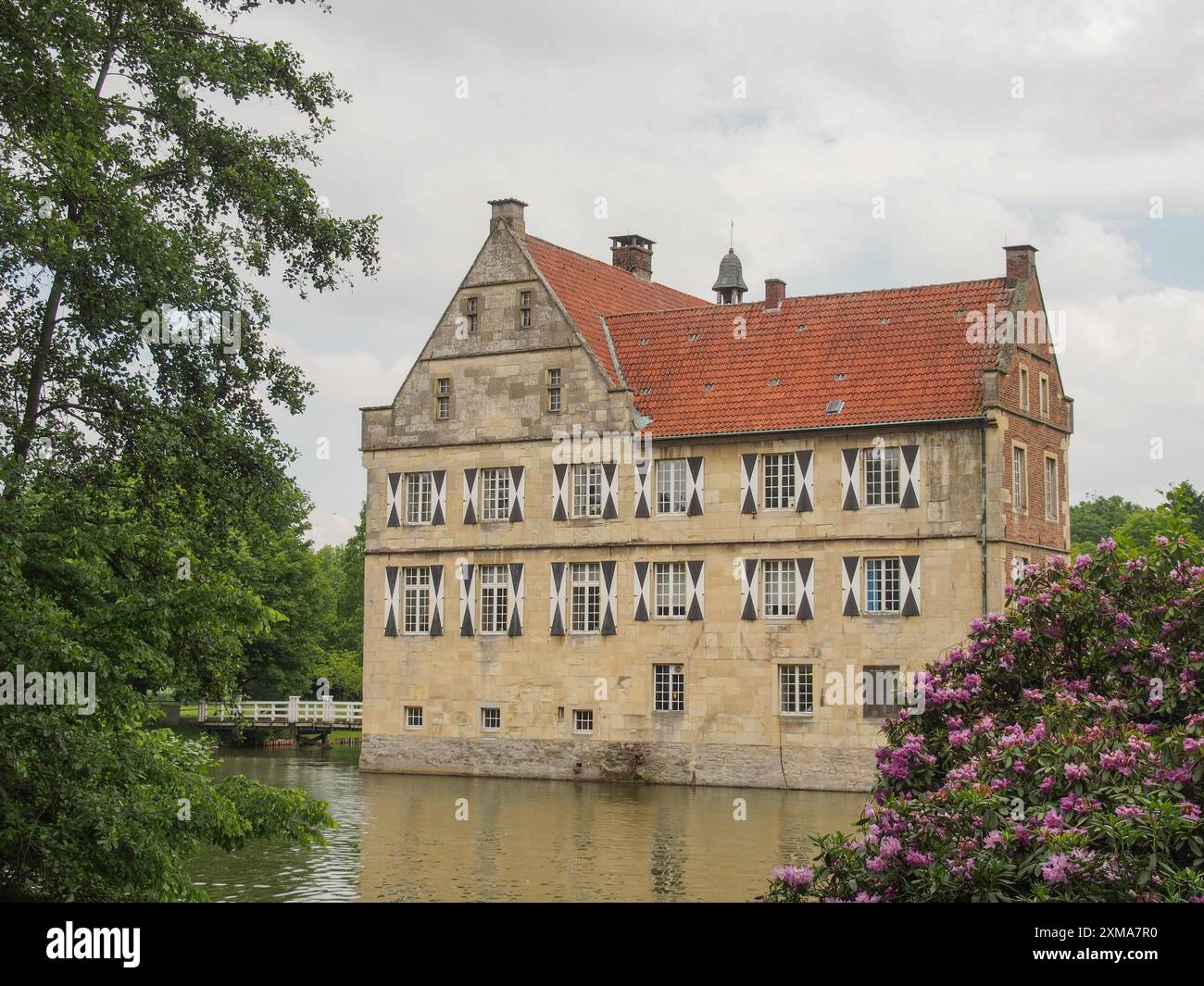 Vieux château par une rivière, entouré par la nature et les arbres, avec l'eau réfléchissante et le ciel bleu, havixbeck, westphalie, allemagne Banque D'Images