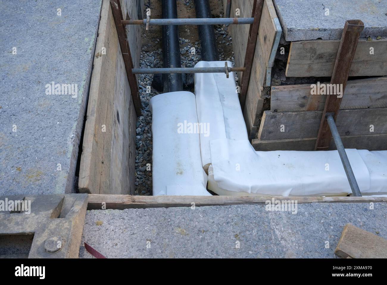 Tranchée de chantier avec tuyaux posés et supports en bois, partie d'une installation Banque D'Images