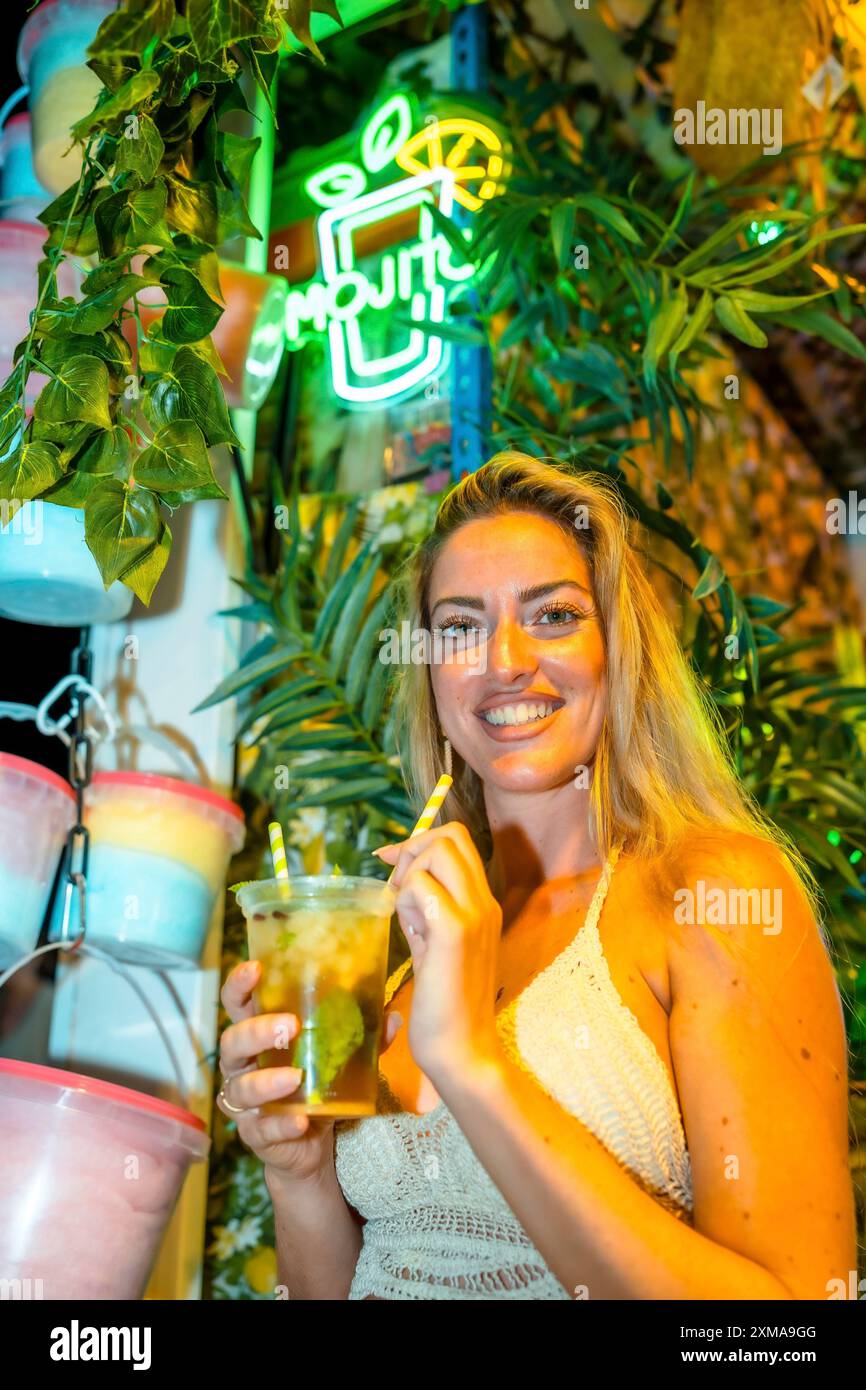 Photo verticale avec espace de copie d'une femme blonde buvant un cocktail mojito sur un bar de nuit Banque D'Images